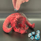 Red fantasy creature figurine with blue and silver dice on a gray background