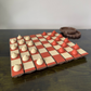 Checkered game board with red and white pieces on a dark surface